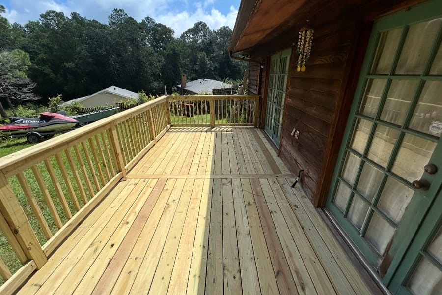 Looking along a new wood deck and railing from a set of French doors