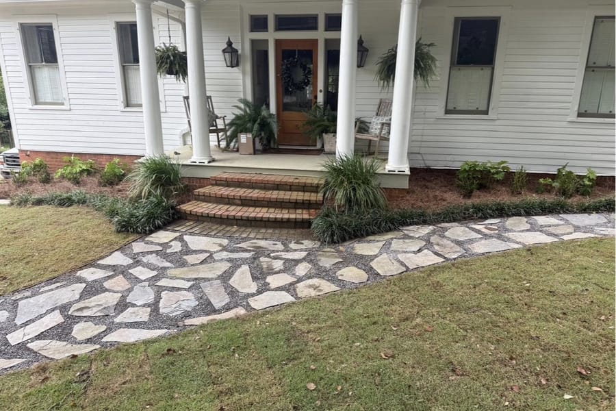 Flagstone walkway ending at brick steps up to a white front porch